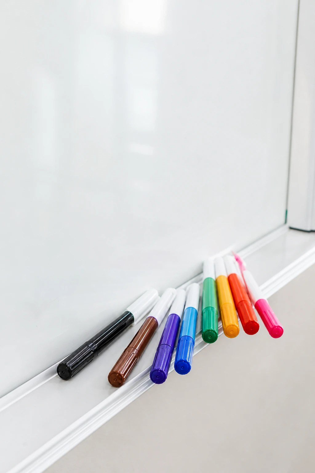 Dry erase markers on a whiteboard tray