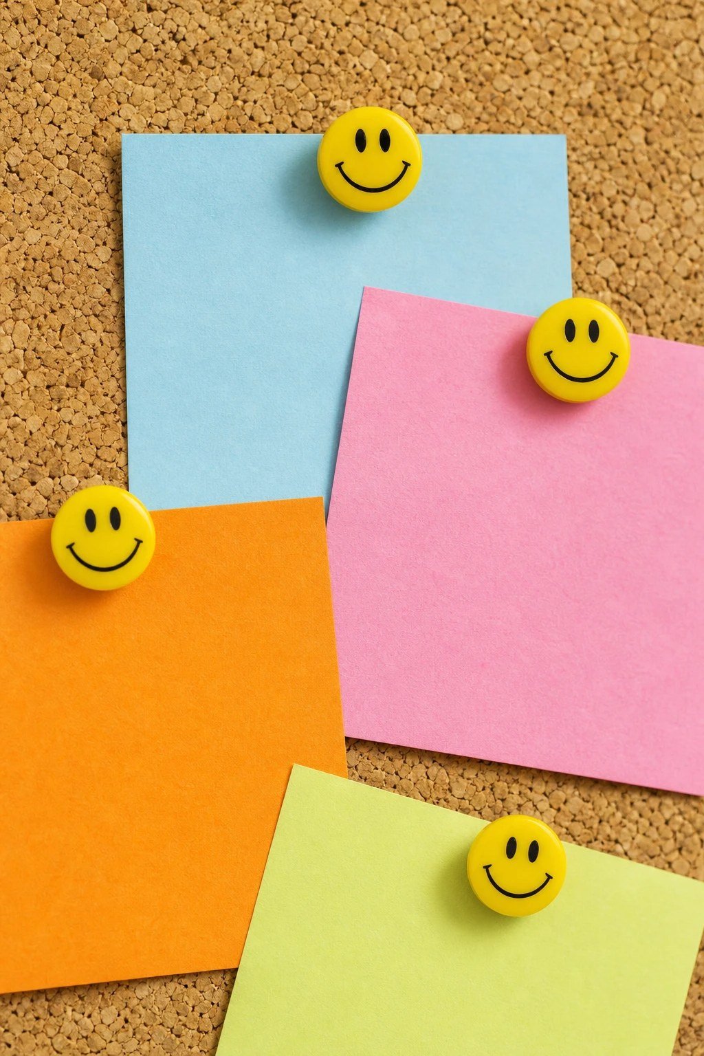 Smiley face push pins on a cork board