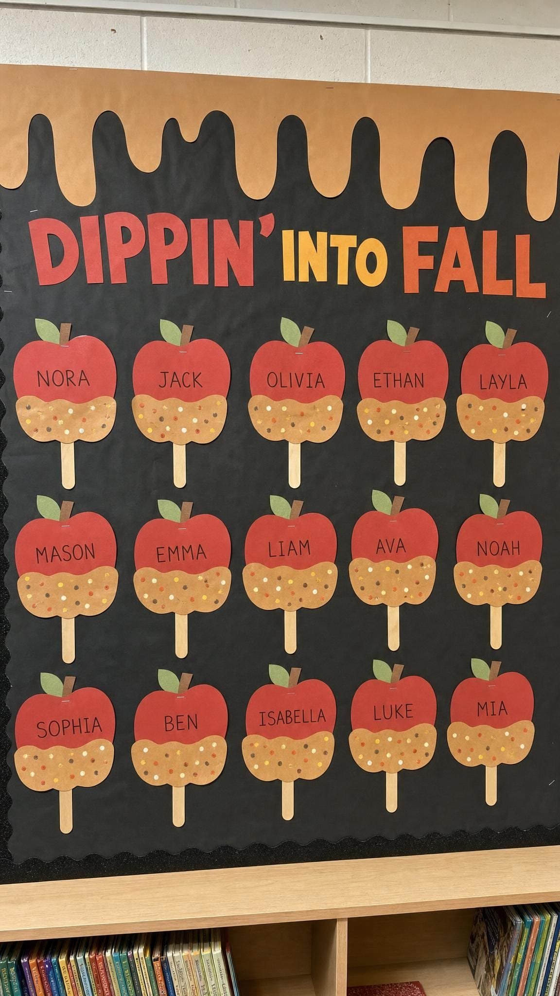 Black bulletin board with paper caramel apples labelled with children's names