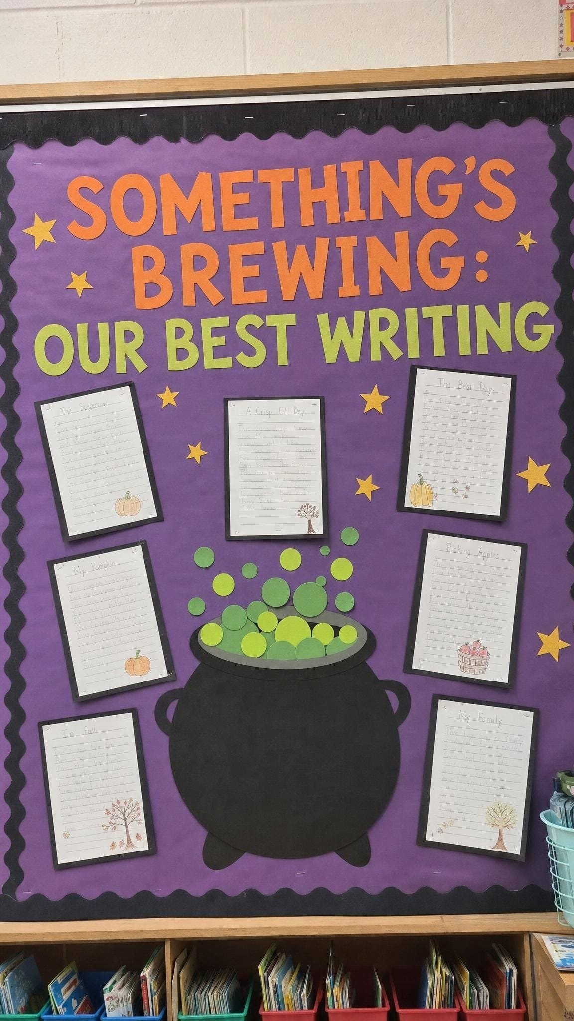 Writing bulletin board with a paper cauldron and green bubbles surrounded by student stories