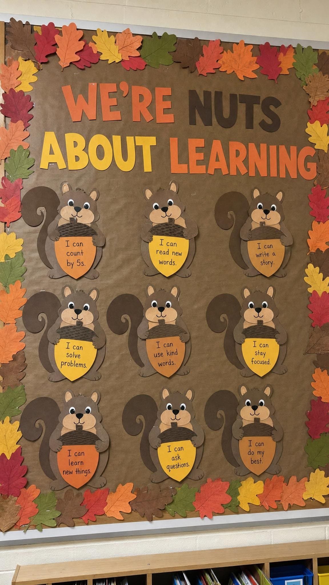 Brown bulletin board with paper squirrels holding acorns with children's learning goals